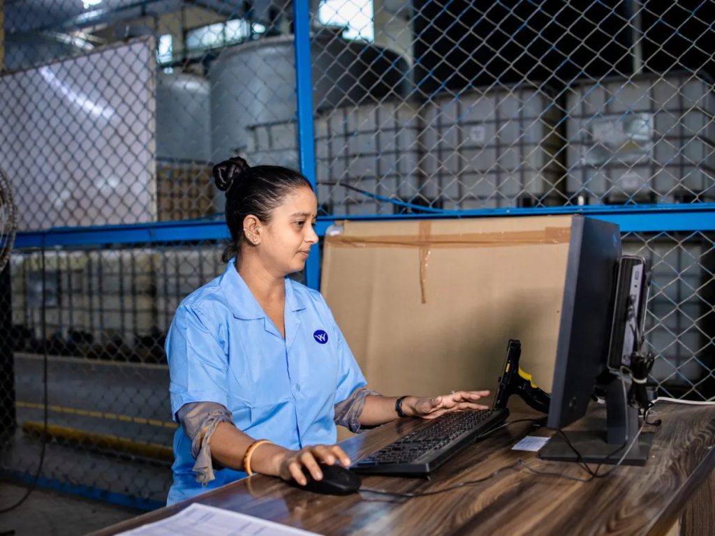 Manufacturing worker using a computer inside an industrial warehouse and production environment