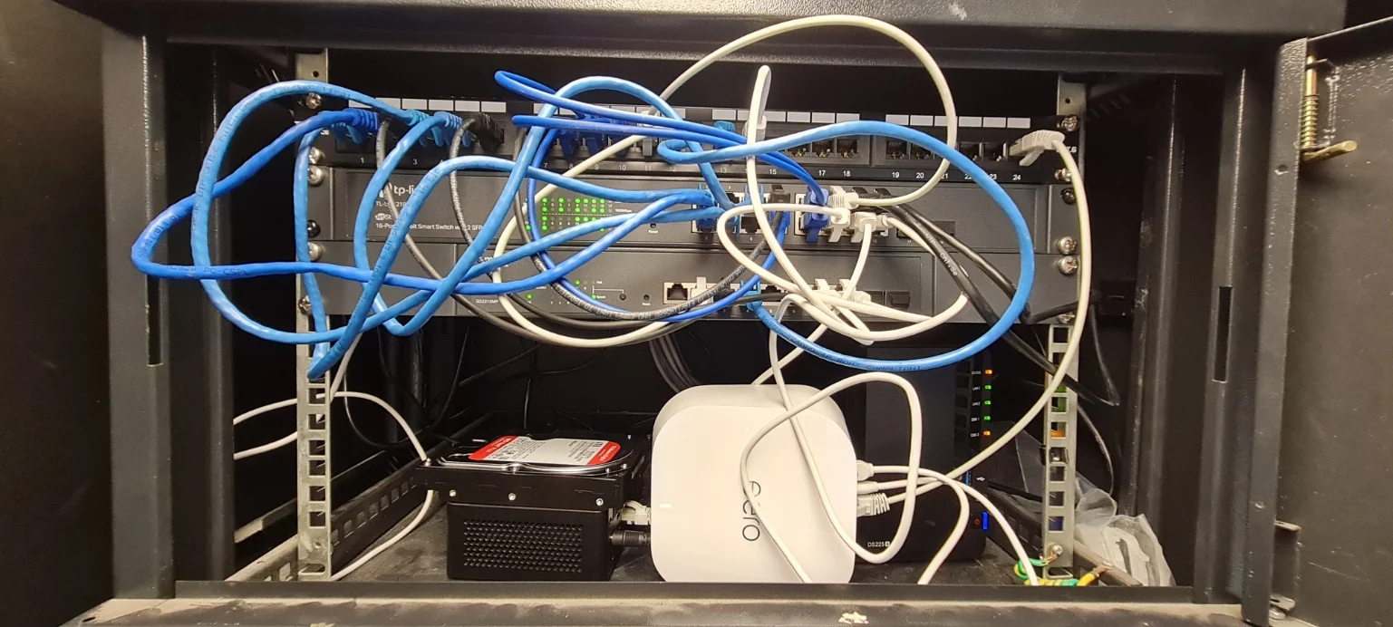 Network cabinet with Intel NUC, eero router, TP-Link 16-port and Omada switches, Synology DS225+ NAS and spare WD hard drive
